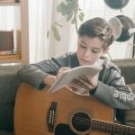 man in gray jacket playing acoustic guitar